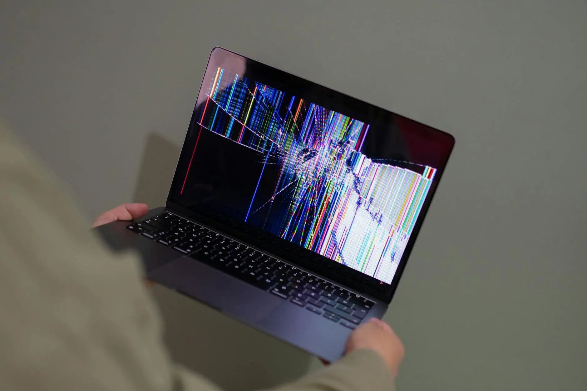Person holding laptop with broken screen