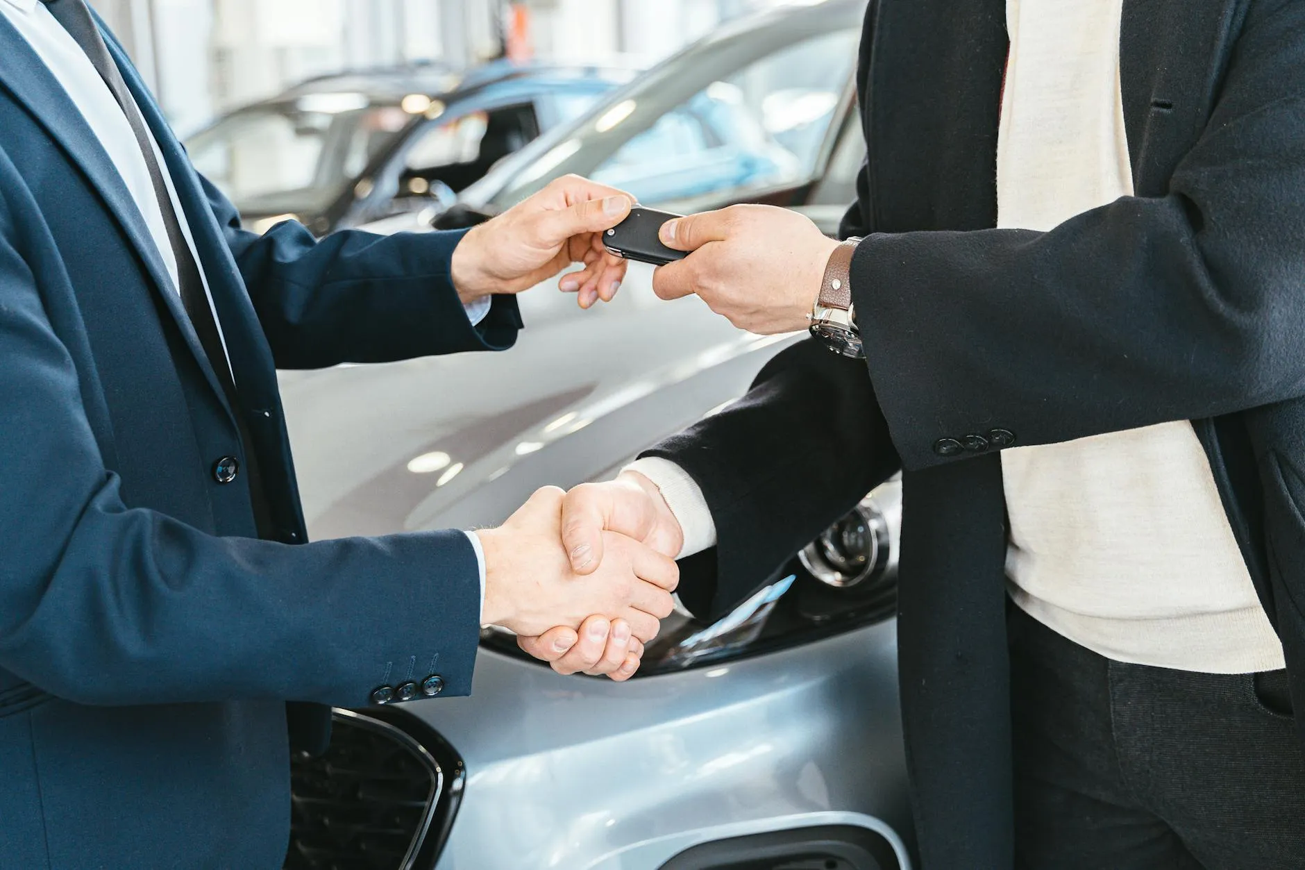Two people exchanging car keys with handshake