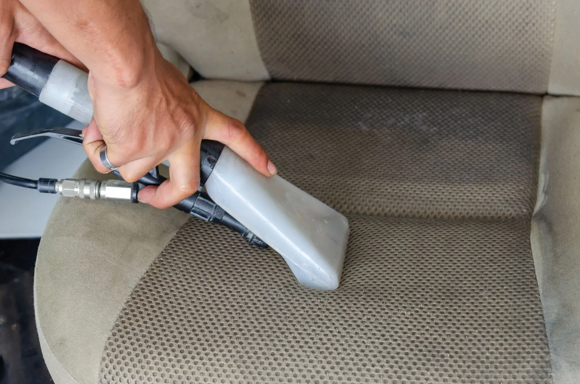 Deep cleaning a used car seat with a vacuum during resale prep