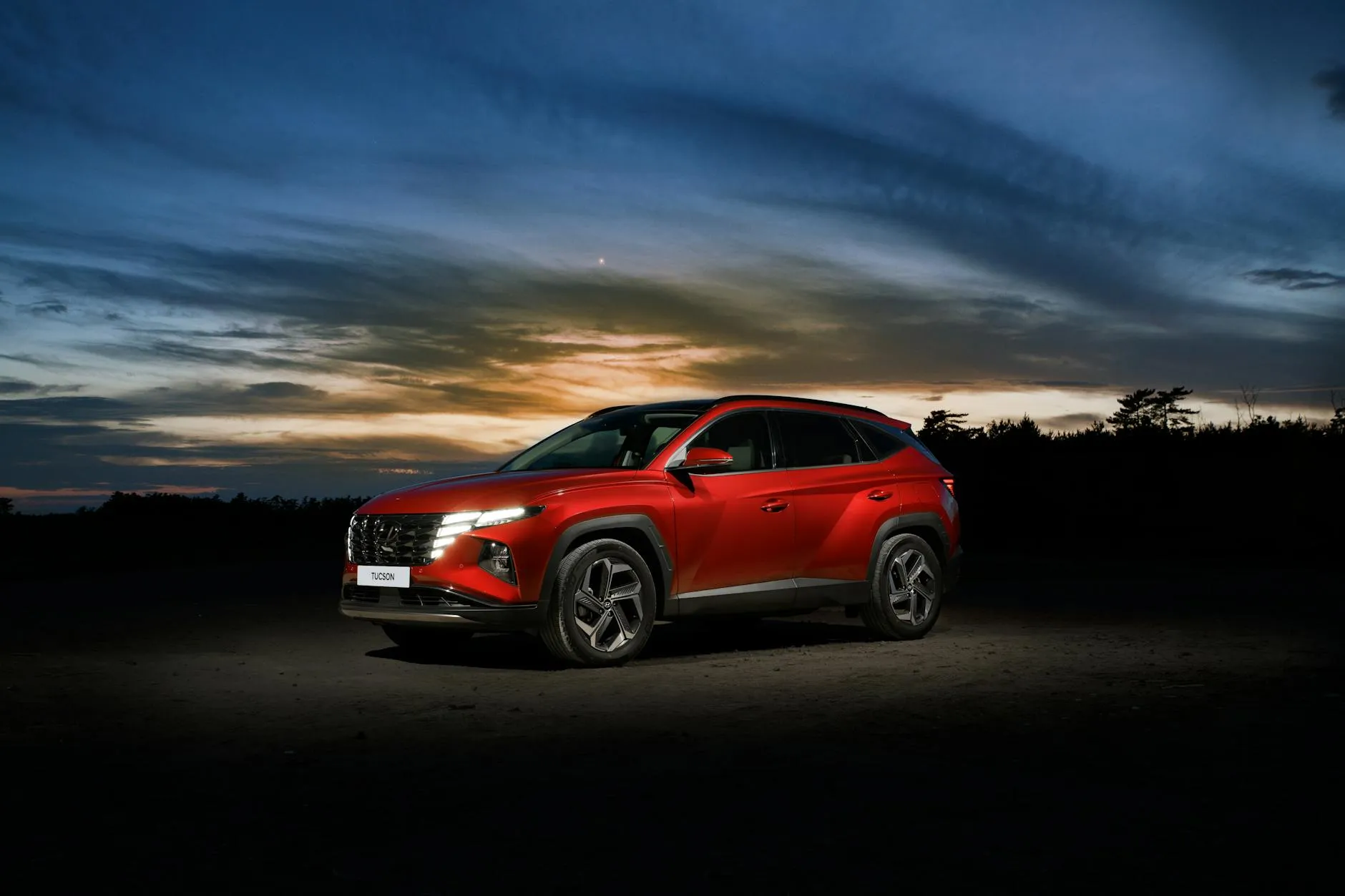 Red Hyundai Tucson SUV at sunset