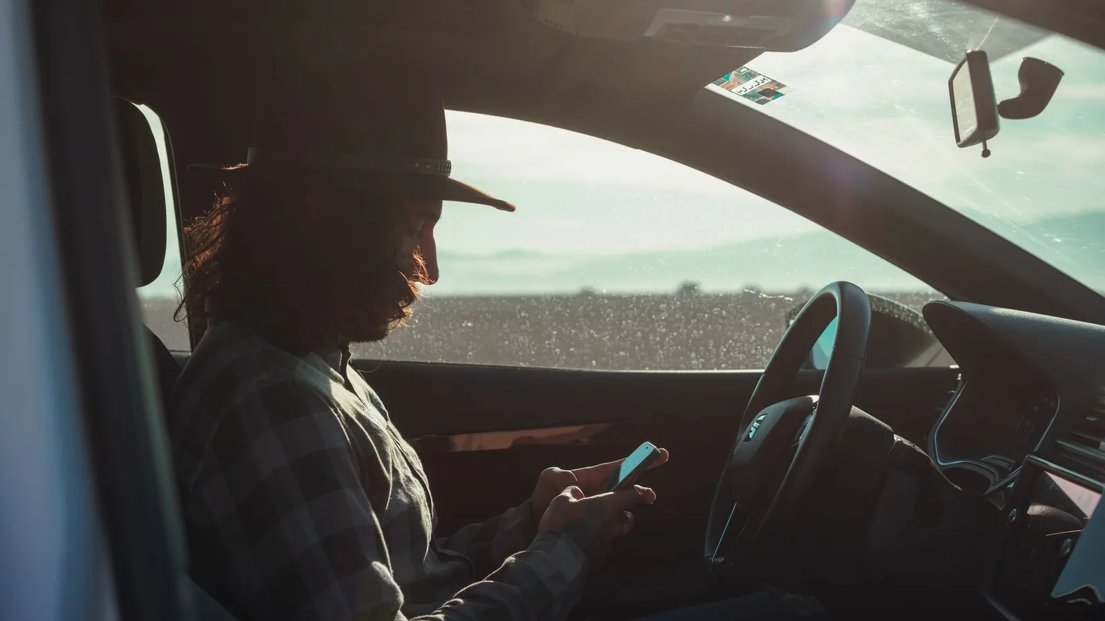 Car buyer sitting in the driver seat checking a Marketplace listing alert on his phone