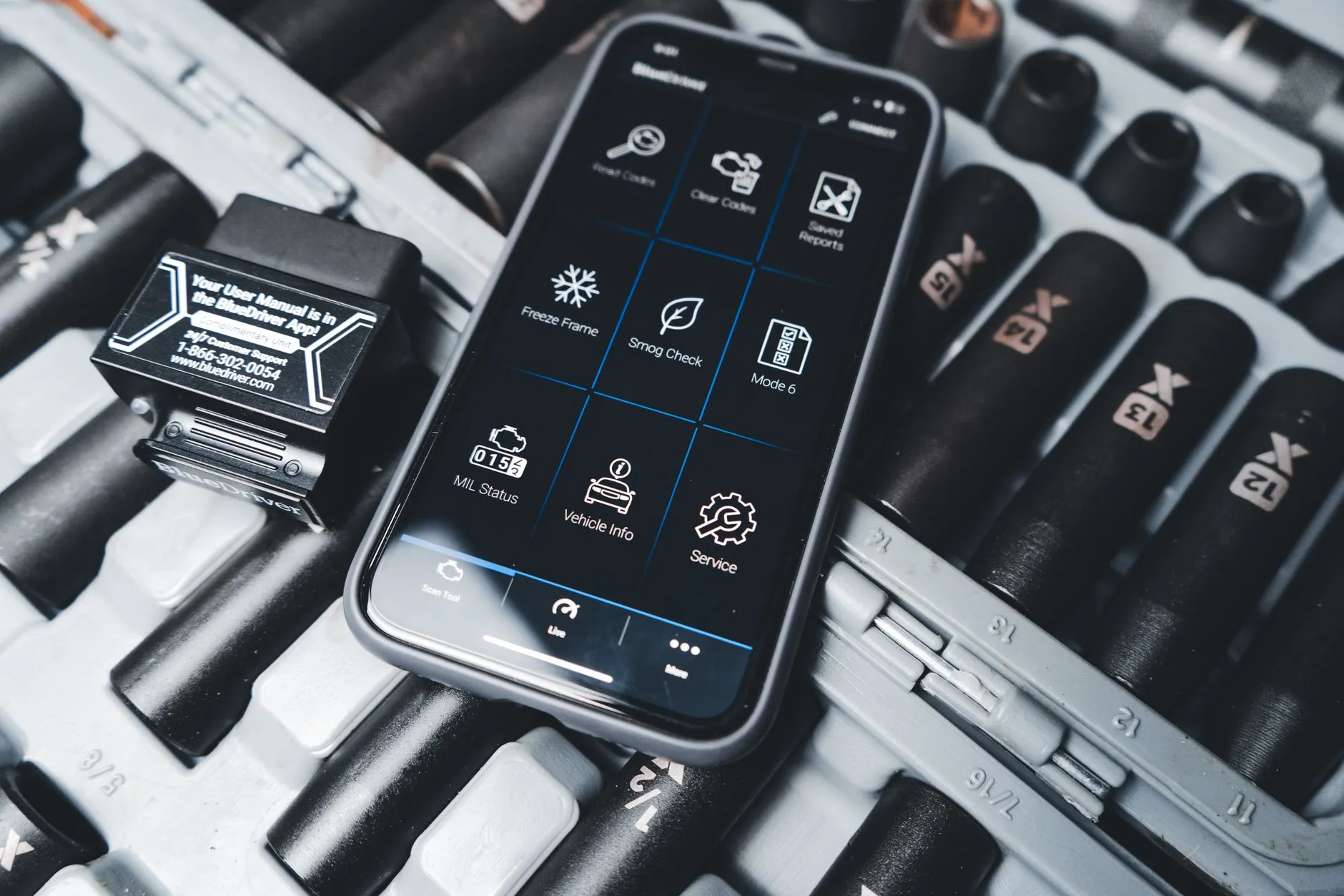 Bluetooth OBD-II scanner paired with a phone diagnostic app during a used car inspection