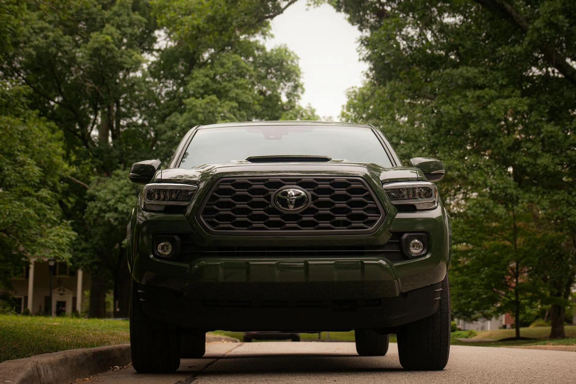 Green Toyota Tacoma truck on suburban street
